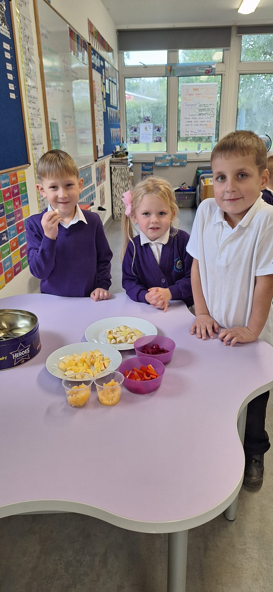 Students stood behind bowls of fruit and vegetables