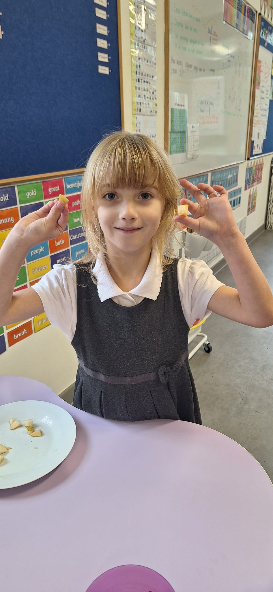 A student holding up pieces of fruit and vegetables