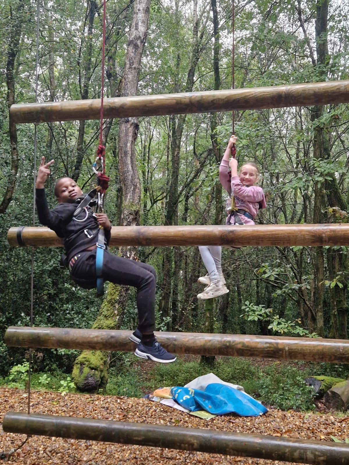 2 students hanging from harnesses, smiling