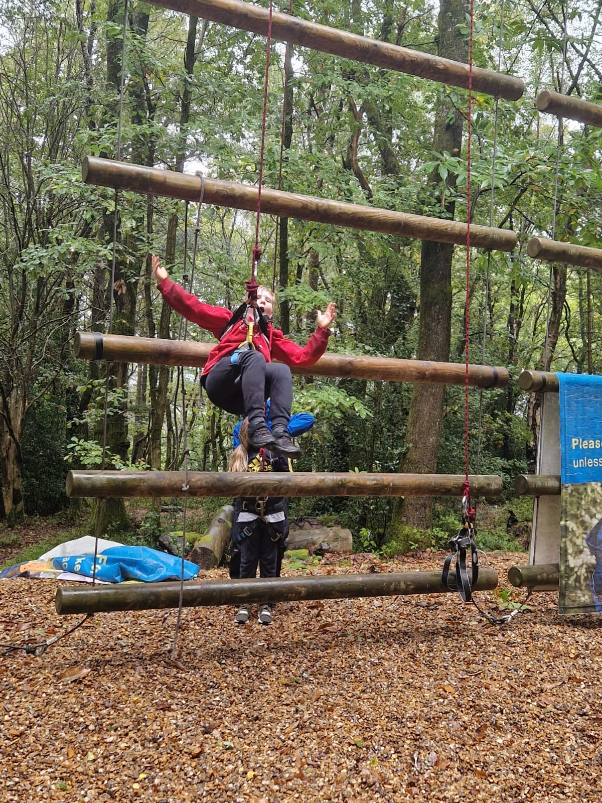 A student hanging from a harness, smiling