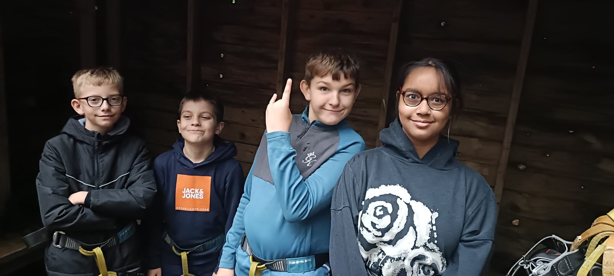4 students in a wooden hut, smiling at the camera