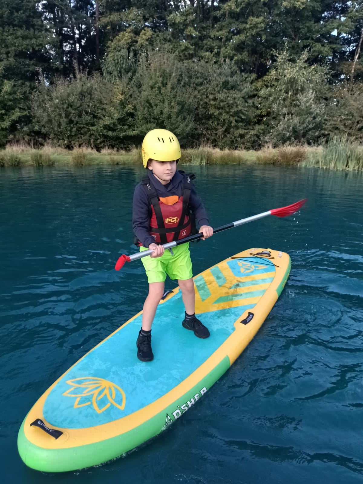 A student standing on a paddle board, smiling