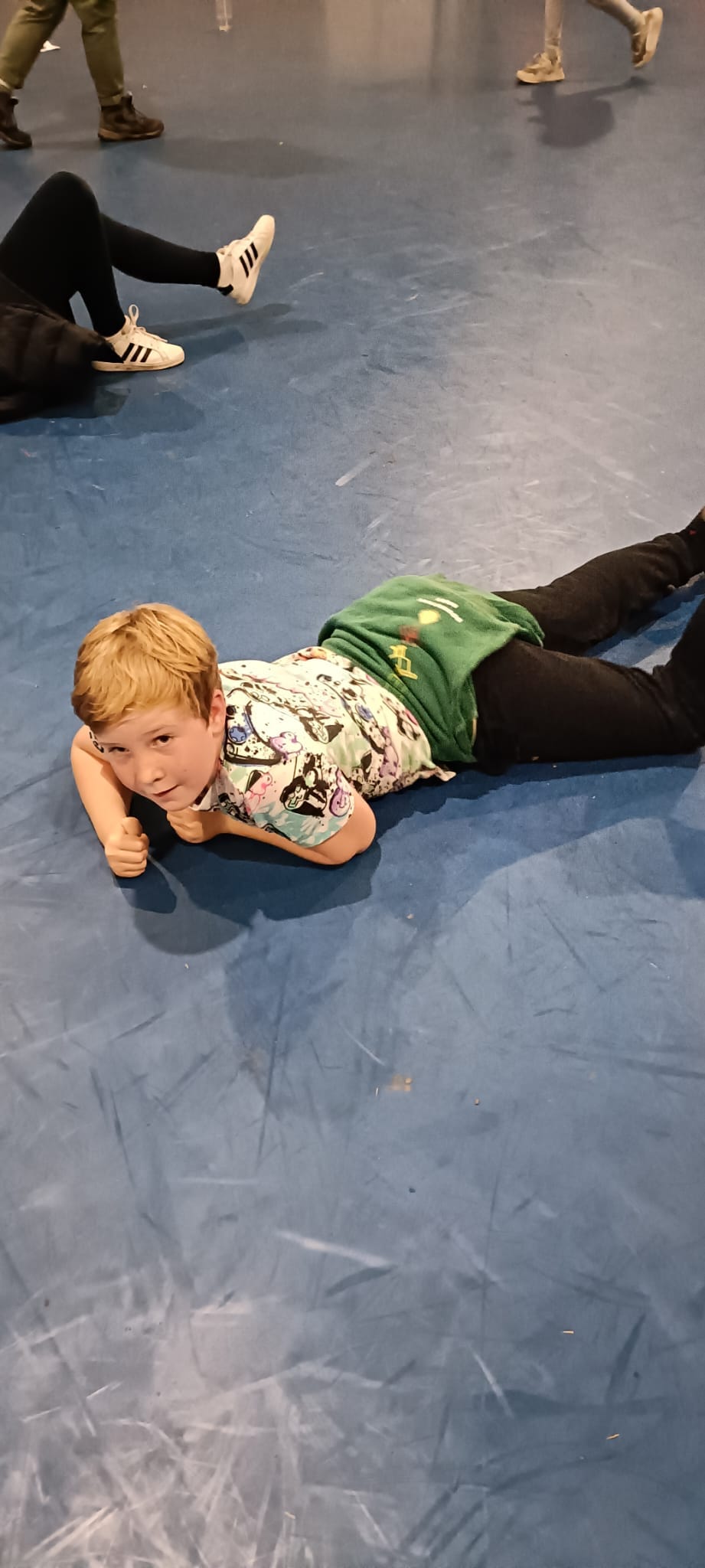 A child laying down on the floor of a sports hall