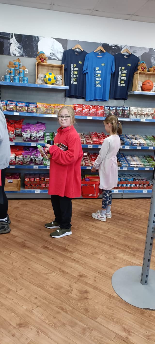 2 students in a shop, looking at sweets