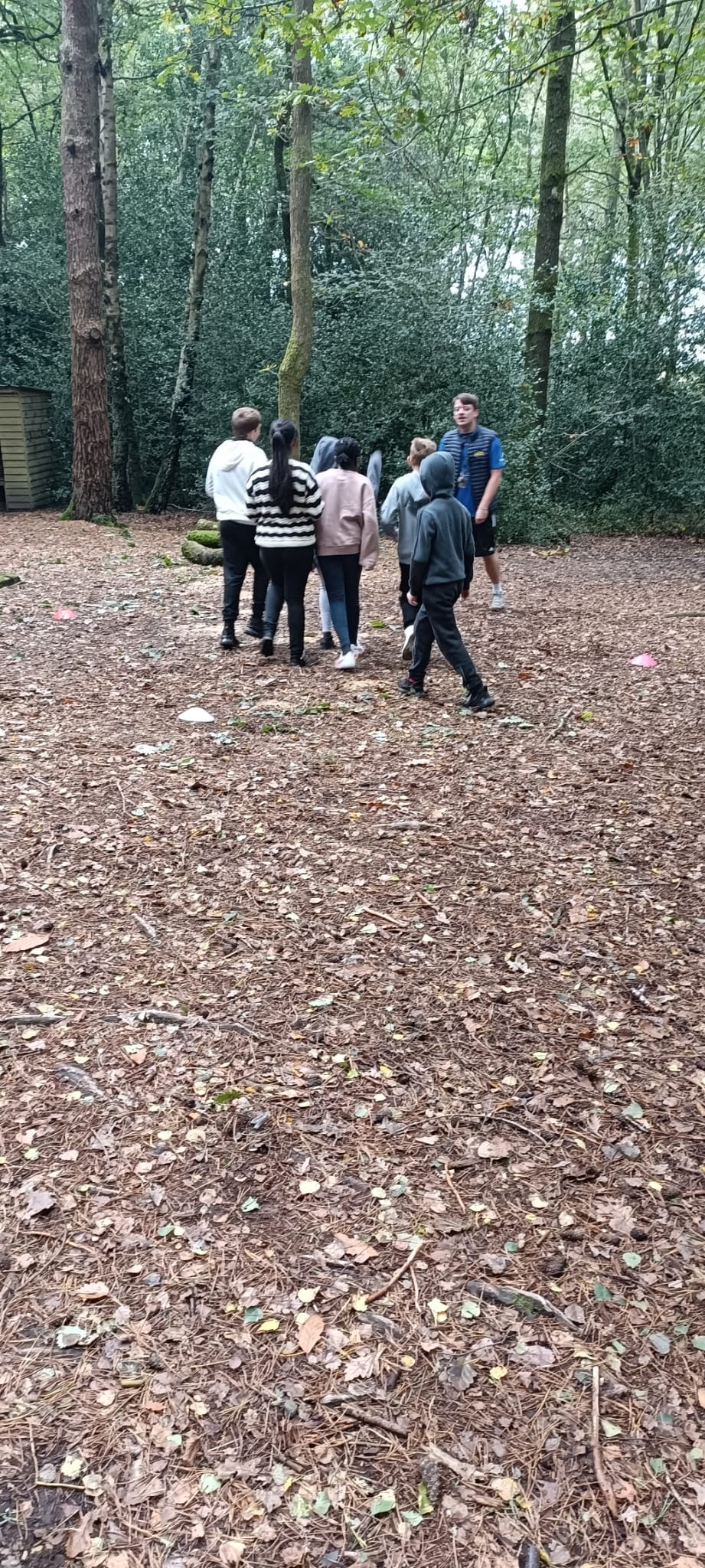 A group of children in a forest, looking at a PGL instructor