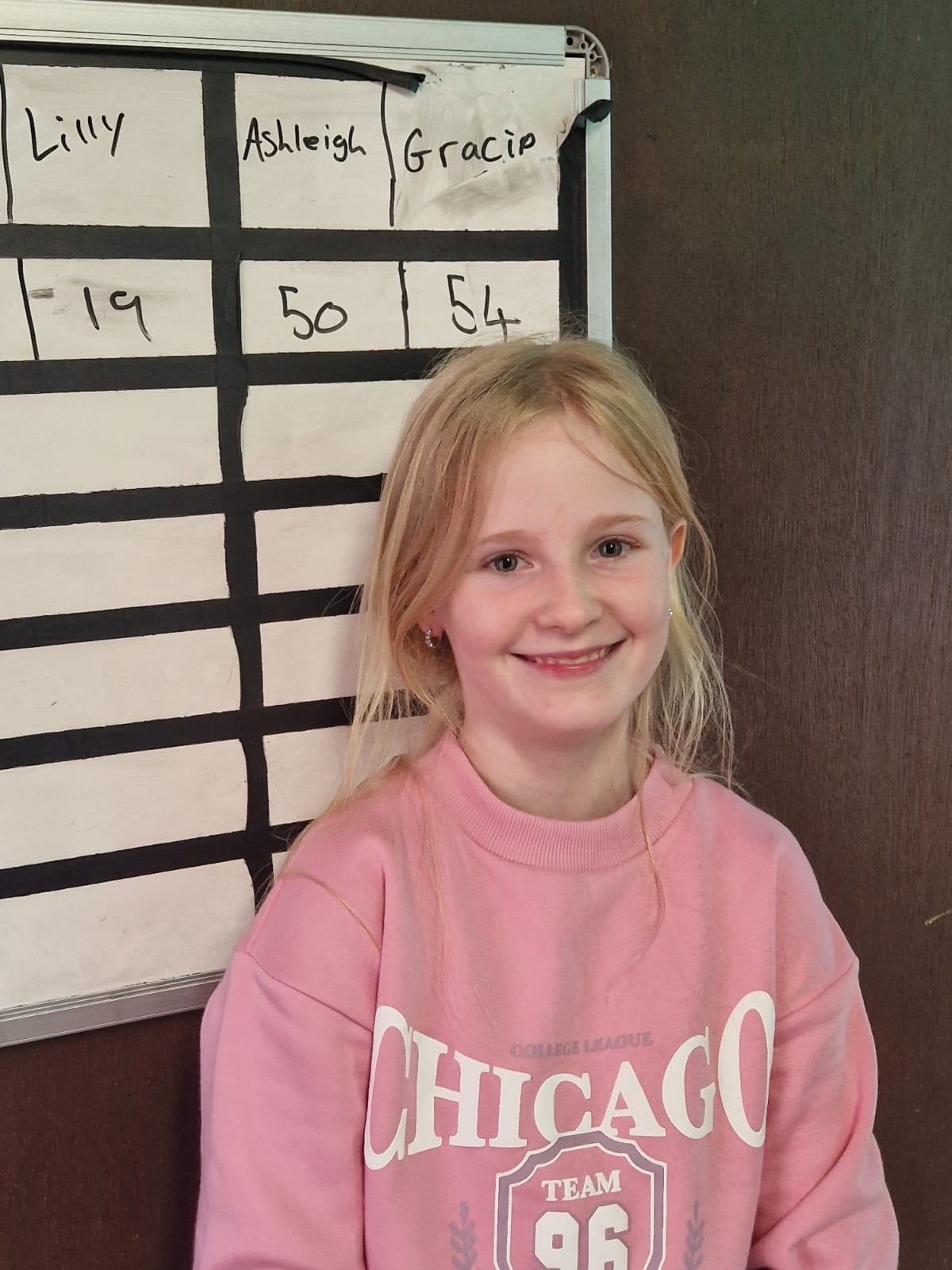 A child stood in front of a whiteboard smiling