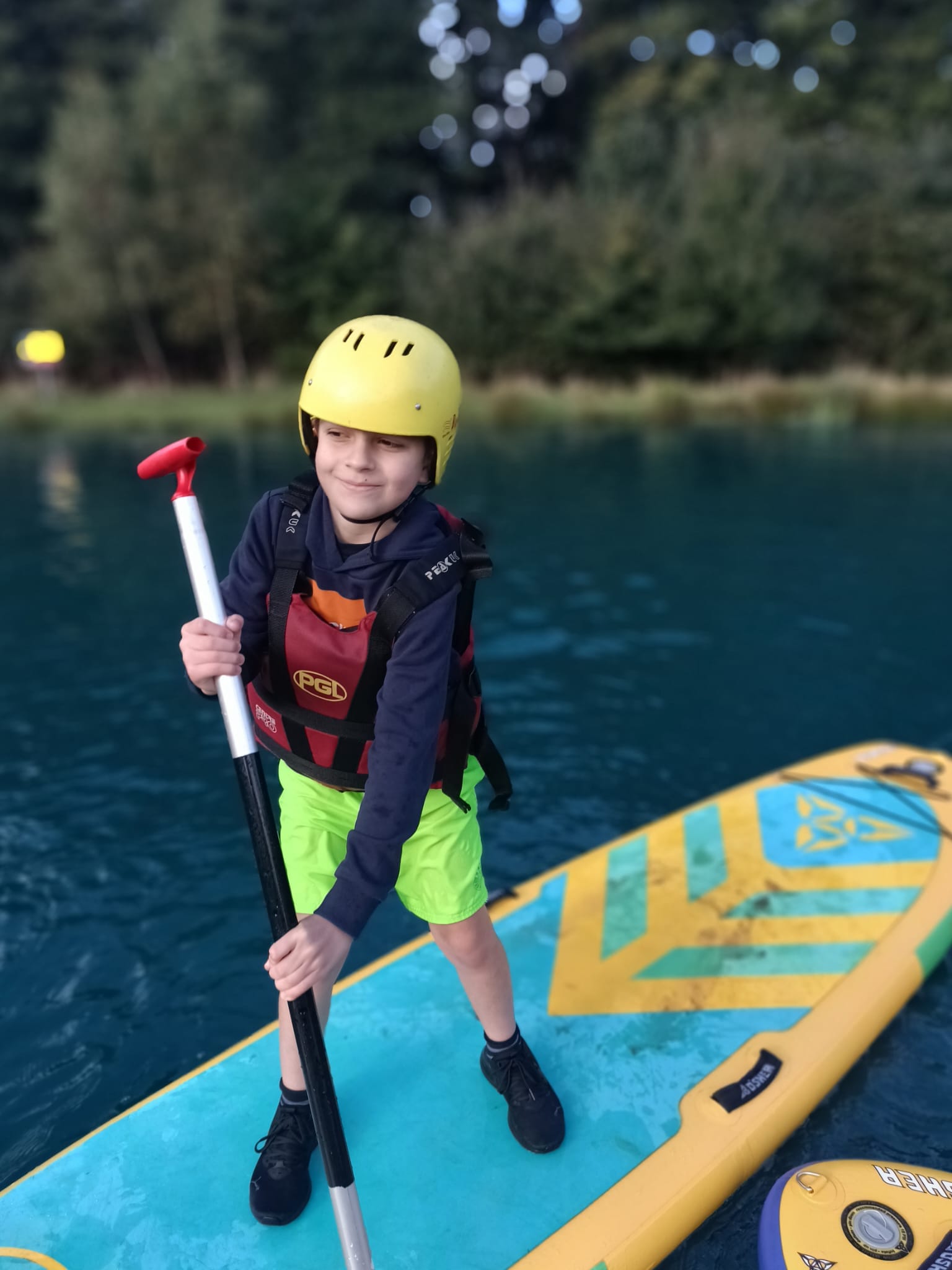 A student standing on a paddle board, smiling