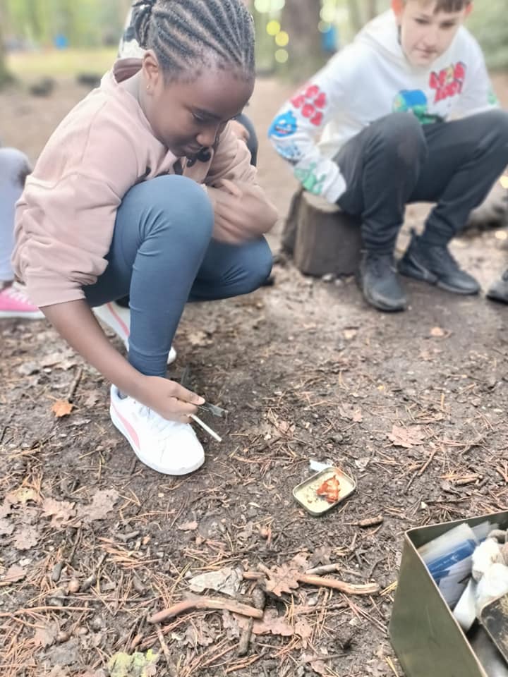 A child starting a small fire on a tin lid