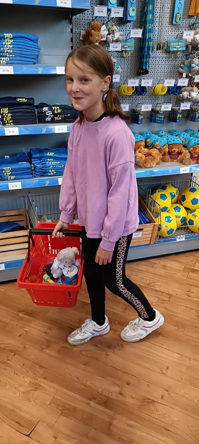 A child in a shop, smiling, holding a basket of items