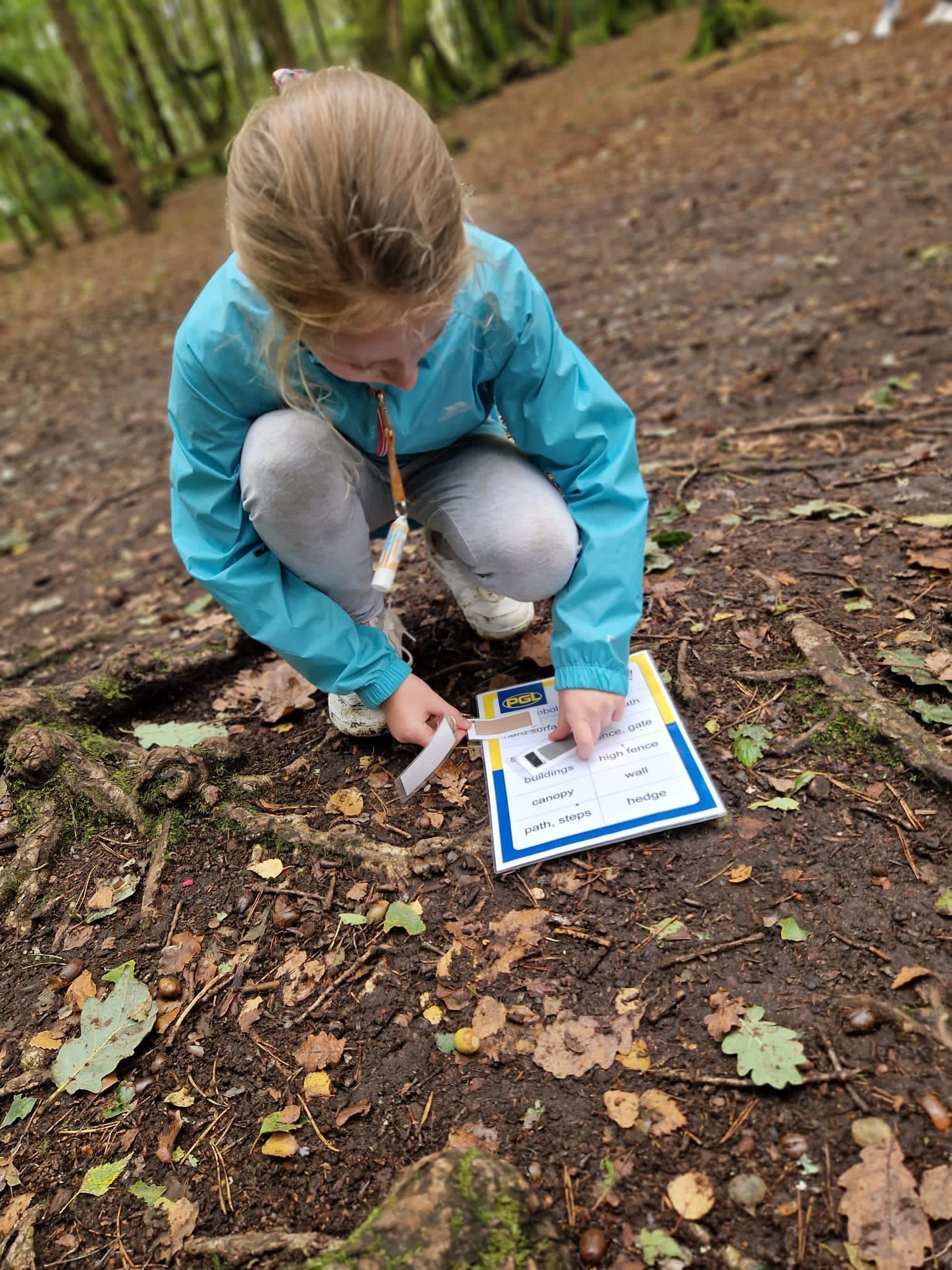 A child crouching in a forest, over a laminated piece of paper