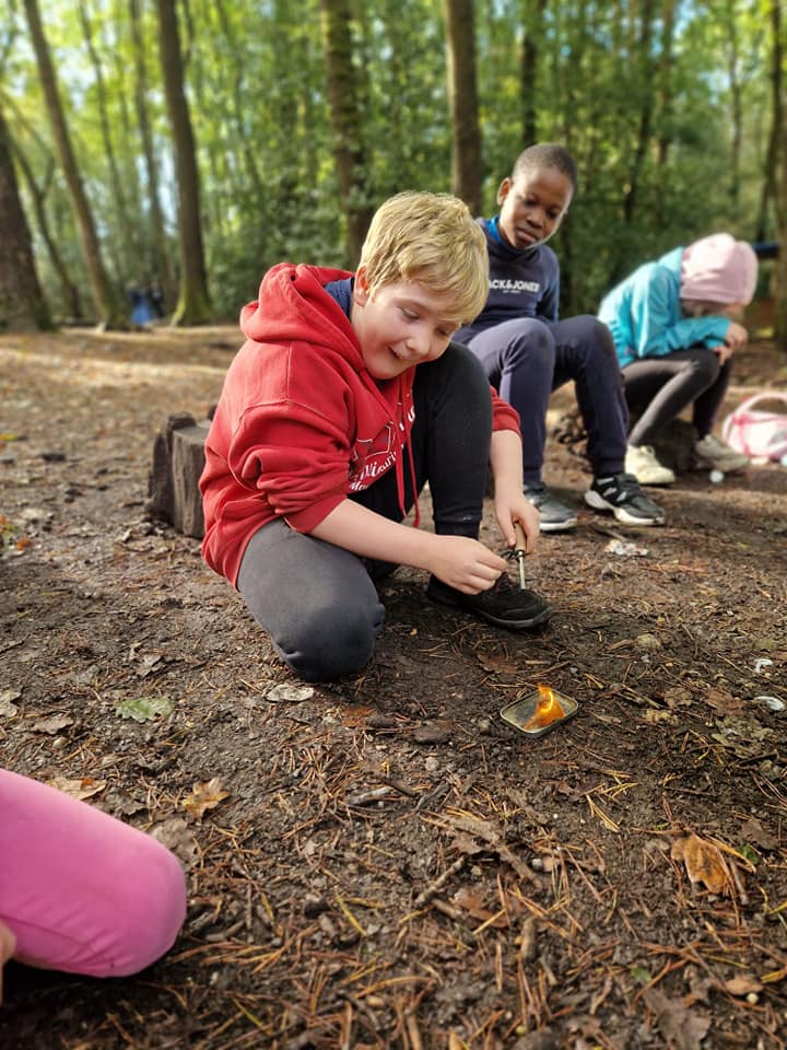A child starting a small fire on a tin lid