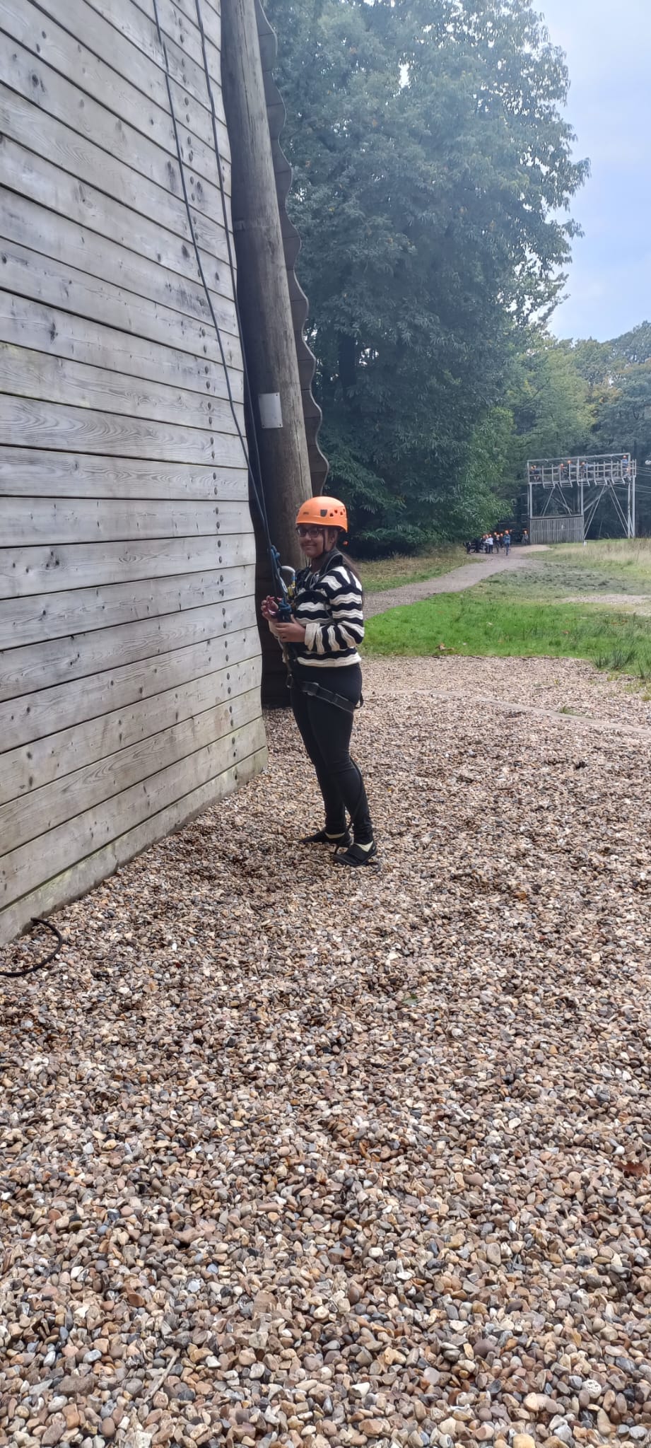 A child stood in a harness at the bottom of an abseiling wall