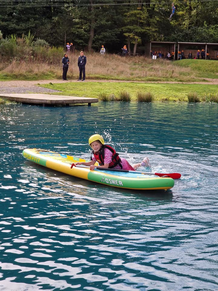 A student laying on a paddle board, smiling
