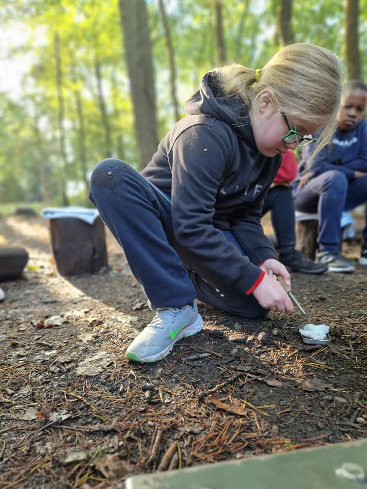 A child starting a small fire on a tin lid