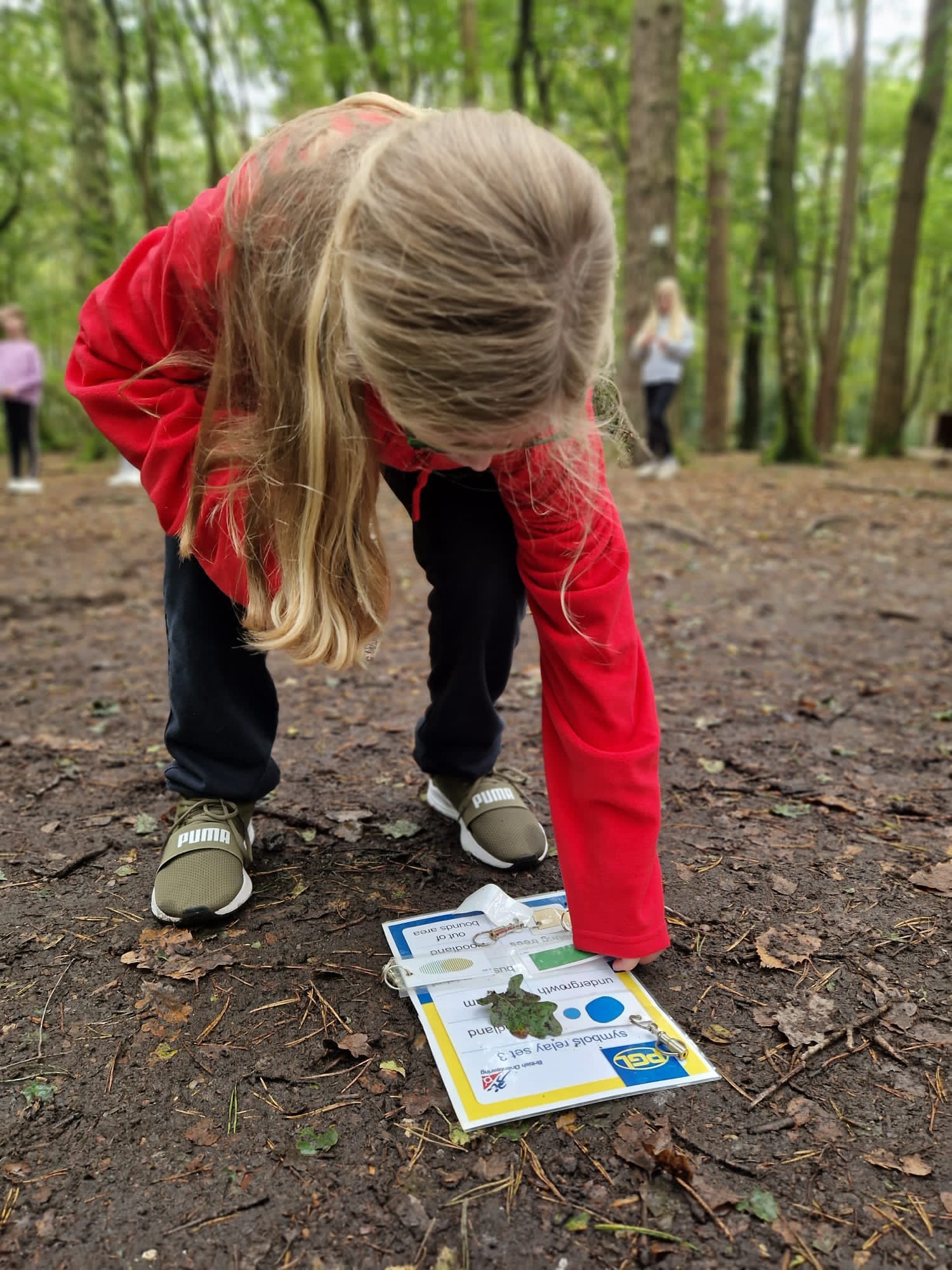A child crouching in a forest, over a laminated piece of paper