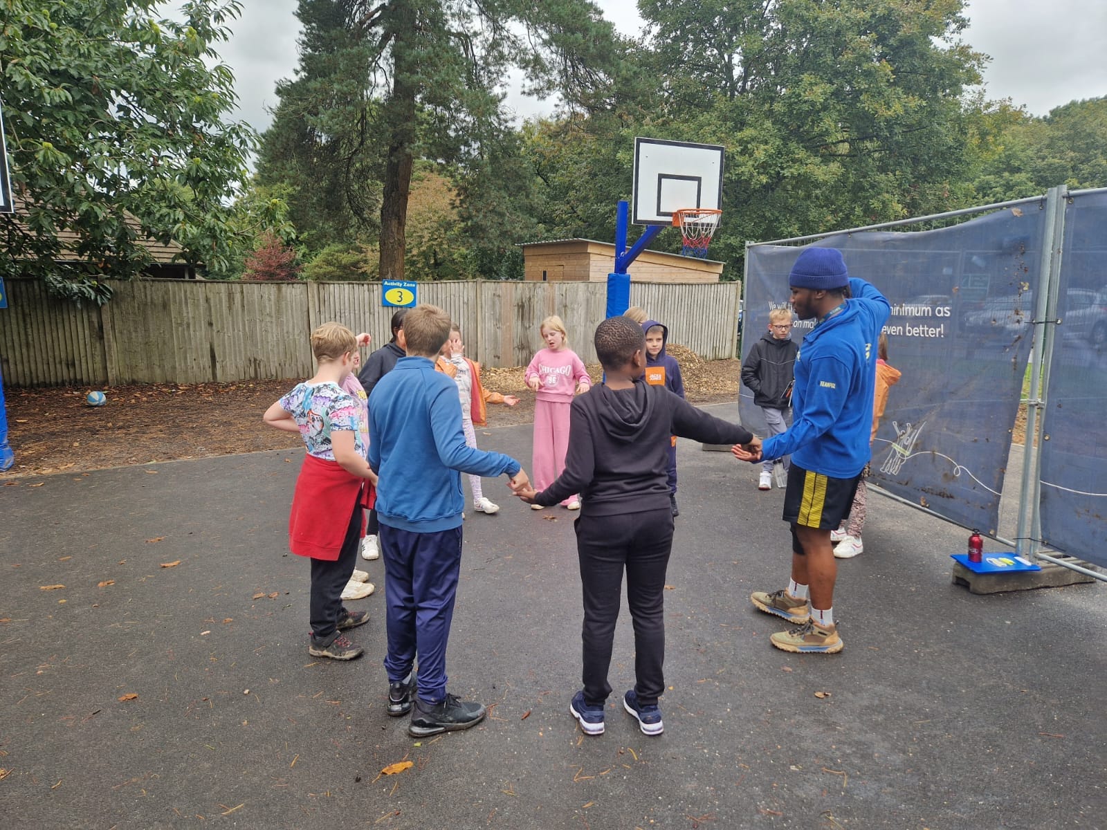 Children stood in a circle holding hands, smiling