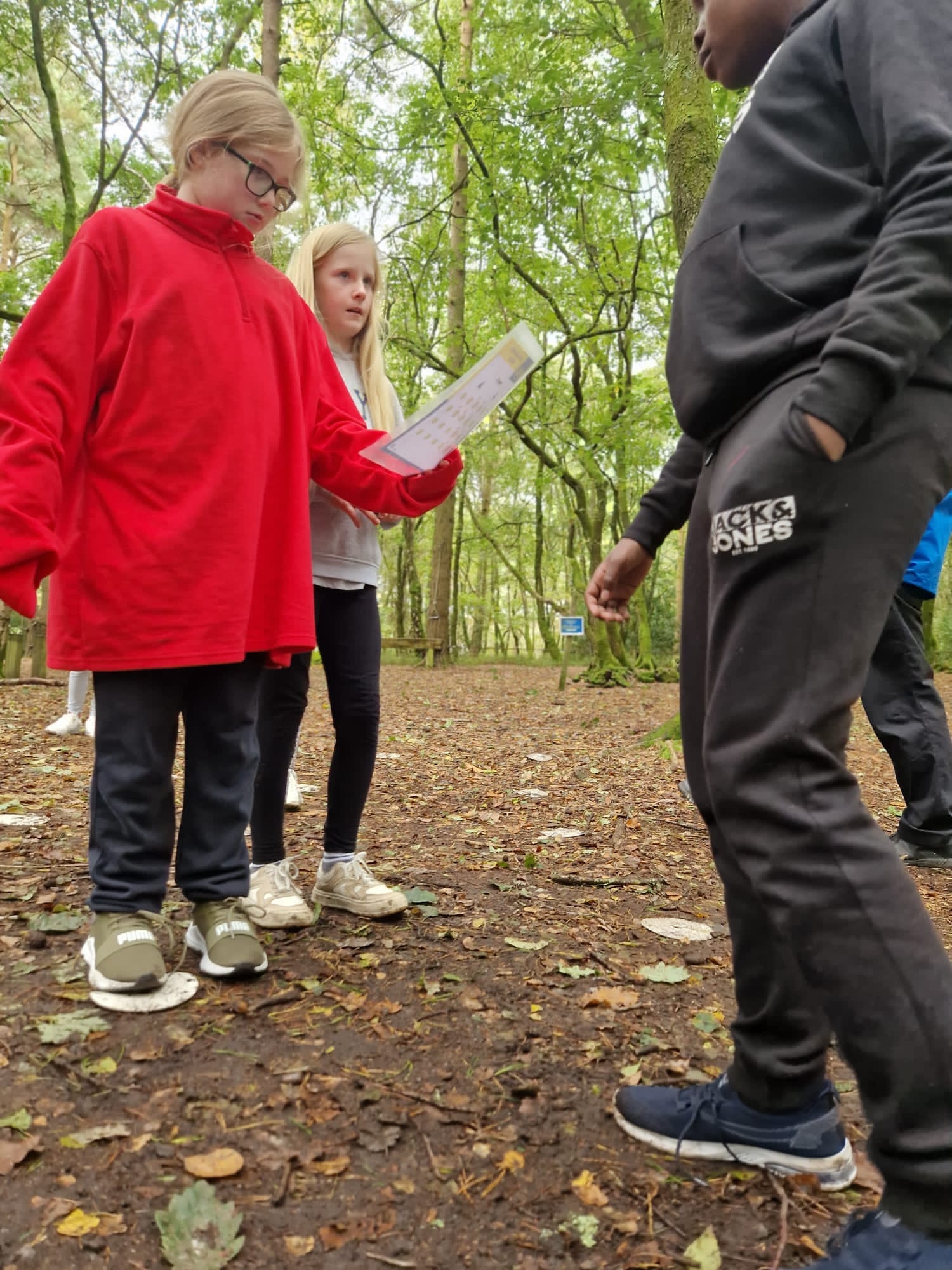 A group of children in a forest, looking at a piece of paper