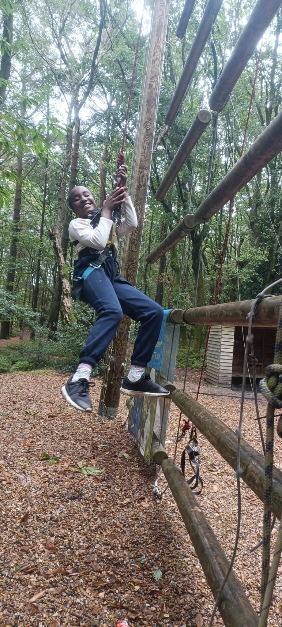 A student hanging from a harness, smiling